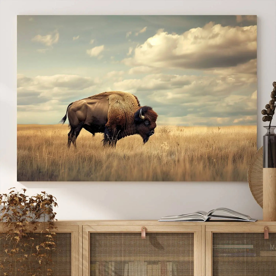 The Sepia American Bison Wall Art Print, a Western canvas print, depicts a bison standing in a grassy field beneath a cloudy sky. This high-resolution museum-quality triptych wall art is ideal for farmhouse wall decor.