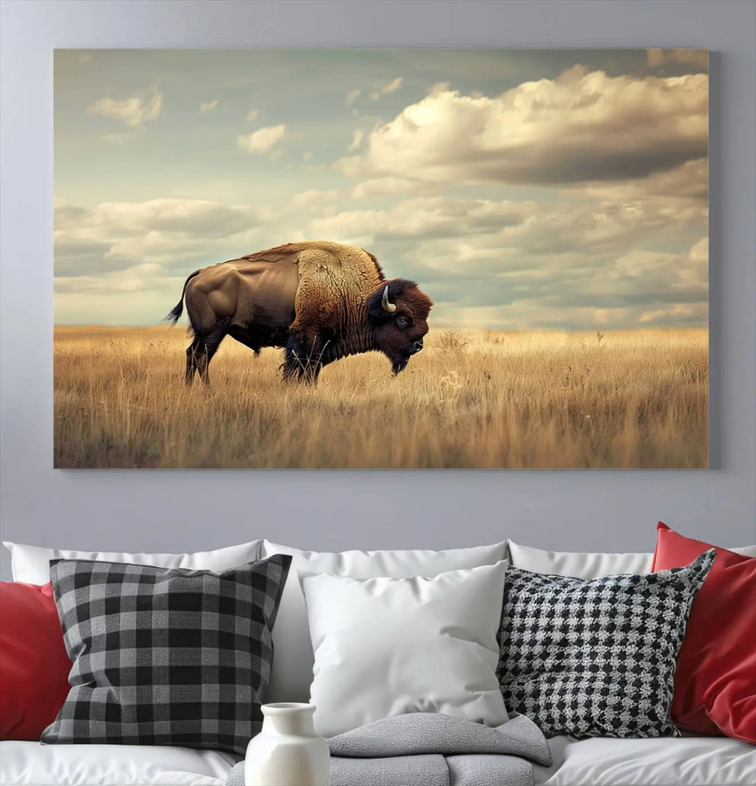 The Sepia American Bison Wall Art Print, a Western canvas print, depicts a bison standing in a grassy field beneath a cloudy sky. This high-resolution museum-quality triptych wall art is ideal for farmhouse wall decor.