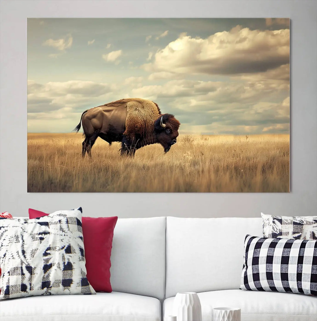 The Sepia American Bison Wall Art Print, a Western canvas print, depicts a bison standing in a grassy field beneath a cloudy sky. This high-resolution museum-quality triptych wall art is ideal for farmhouse wall decor.