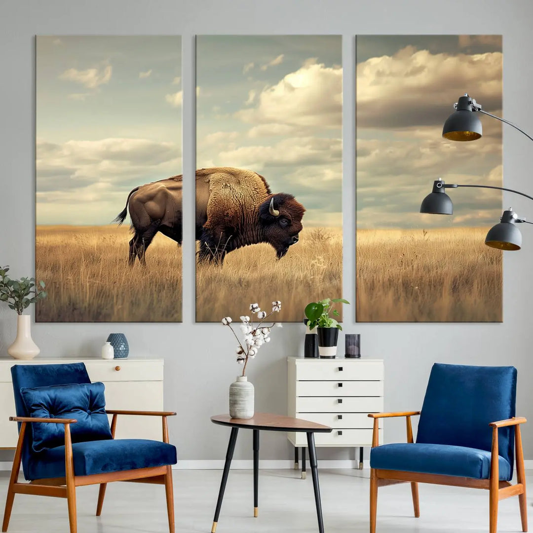 The Sepia American Bison Wall Art Print, a Western canvas print, depicts a bison standing in a grassy field beneath a cloudy sky. This high-resolution museum-quality triptych wall art is ideal for farmhouse wall decor.