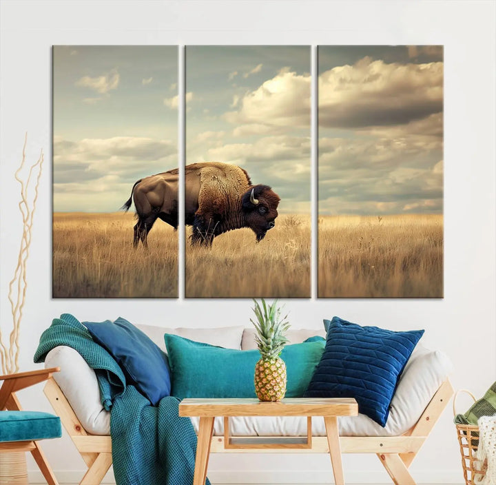 The Sepia American Bison Wall Art Print, a Western canvas print, depicts a bison standing in a grassy field beneath a cloudy sky. This high-resolution museum-quality triptych wall art is ideal for farmhouse wall decor.