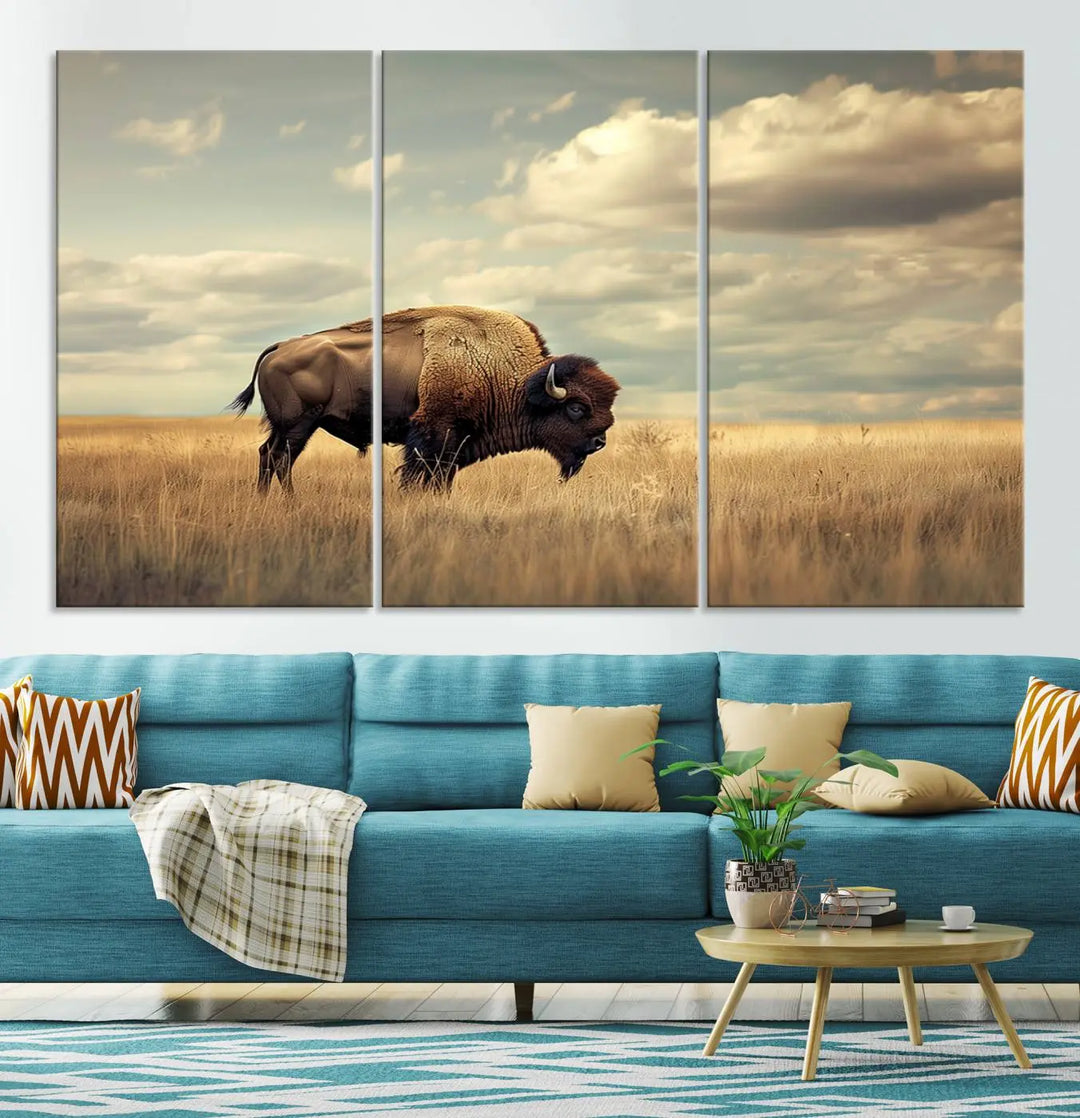 The Sepia American Bison Wall Art Print, a Western canvas print, depicts a bison standing in a grassy field beneath a cloudy sky. This high-resolution museum-quality triptych wall art is ideal for farmhouse wall decor.