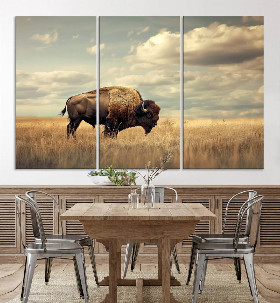 The Sepia American Bison Wall Art Print, a Western canvas print, depicts a bison standing in a grassy field beneath a cloudy sky. This high-resolution museum-quality triptych wall art is ideal for farmhouse wall decor.