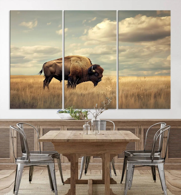 The Sepia American Bison Wall Art Print, a Western canvas print, depicts a bison standing in a grassy field beneath a cloudy sky. This high-resolution museum-quality triptych wall art is ideal for farmhouse wall decor.