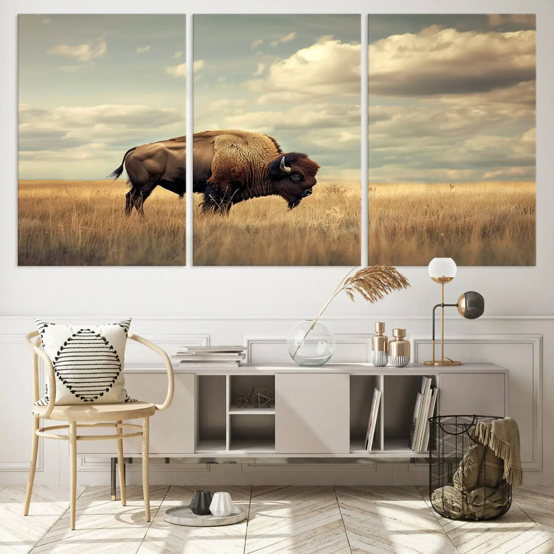 The Sepia American Bison Wall Art Print, a Western canvas print, depicts a bison standing in a grassy field beneath a cloudy sky. This high-resolution museum-quality triptych wall art is ideal for farmhouse wall decor.