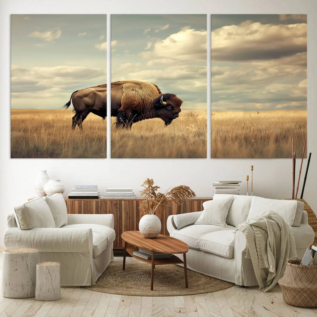 The Sepia American Bison Wall Art Print, a Western canvas print, depicts a bison standing in a grassy field beneath a cloudy sky. This high-resolution museum-quality triptych wall art is ideal for farmhouse wall decor.