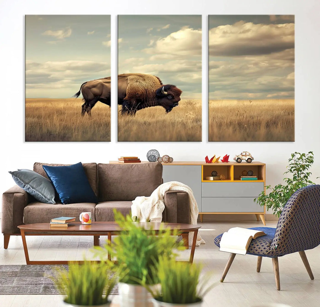 The Sepia American Bison Wall Art Print, a Western canvas print, depicts a bison standing in a grassy field beneath a cloudy sky. This high-resolution museum-quality triptych wall art is ideal for farmhouse wall decor.