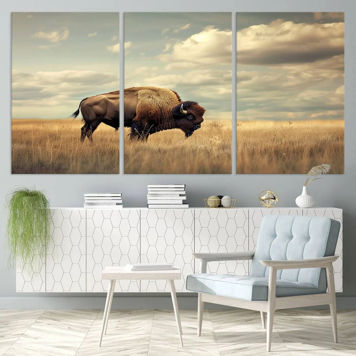 The Sepia American Bison Wall Art Print, a Western canvas print, depicts a bison standing in a grassy field beneath a cloudy sky. This high-resolution museum-quality triptych wall art is ideal for farmhouse wall decor.