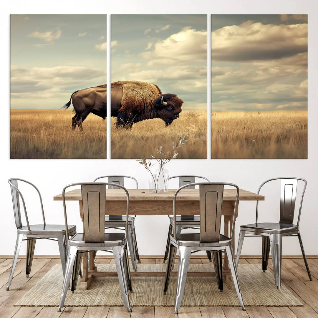 The Sepia American Bison Wall Art Print, a Western canvas print, depicts a bison standing in a grassy field beneath a cloudy sky. This high-resolution museum-quality triptych wall art is ideal for farmhouse wall decor.