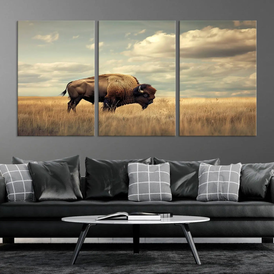 The Sepia American Bison Wall Art Print, a Western canvas print, depicts a bison standing in a grassy field beneath a cloudy sky. This high-resolution museum-quality triptych wall art is ideal for farmhouse wall decor.