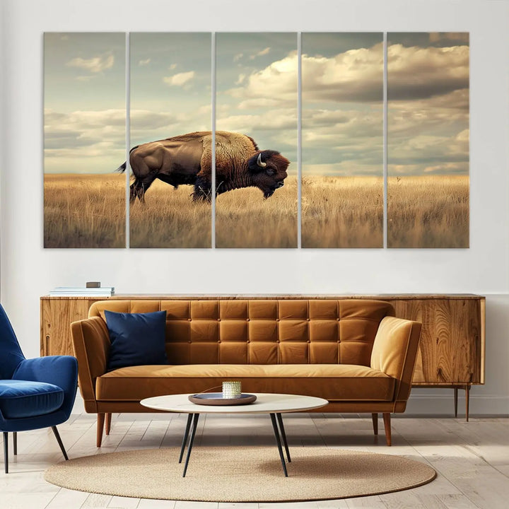 The Sepia American Bison Wall Art Print, a Western canvas print, depicts a bison standing in a grassy field beneath a cloudy sky. This high-resolution museum-quality triptych wall art is ideal for farmhouse wall decor.