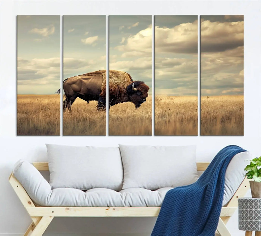 The Sepia American Bison Wall Art Print, a Western canvas print, depicts a bison standing in a grassy field beneath a cloudy sky. This high-resolution museum-quality triptych wall art is ideal for farmhouse wall decor.