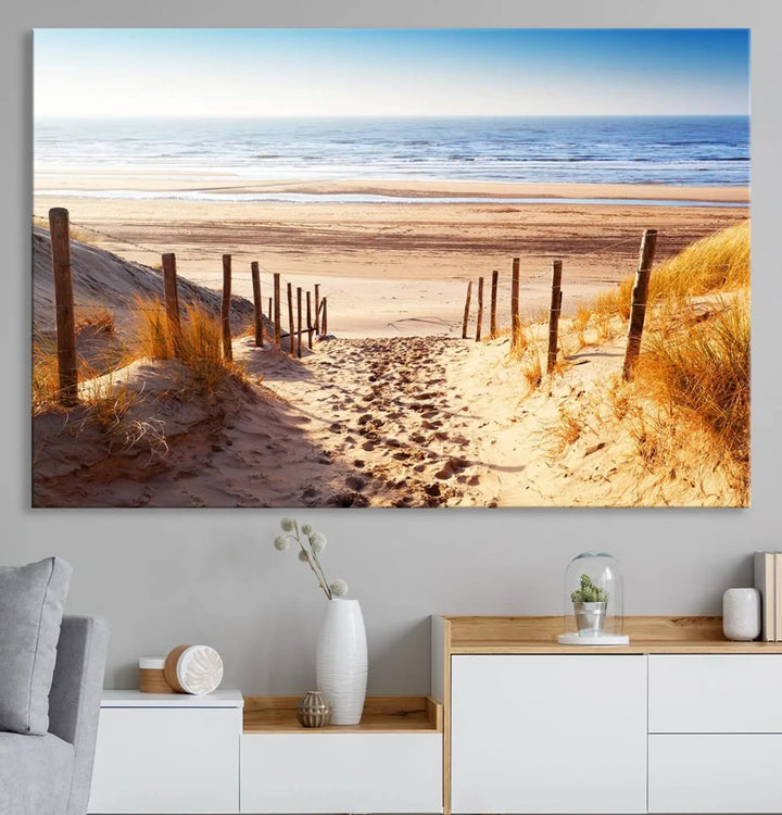 A triptych of Serene Beach Path Canvas Art, a giclee canvas print with gallery wrap, adorns the wall. This stunning coastal sand dunes wall art, crafted with Canon print quality, adds a tranquil touch to the space.