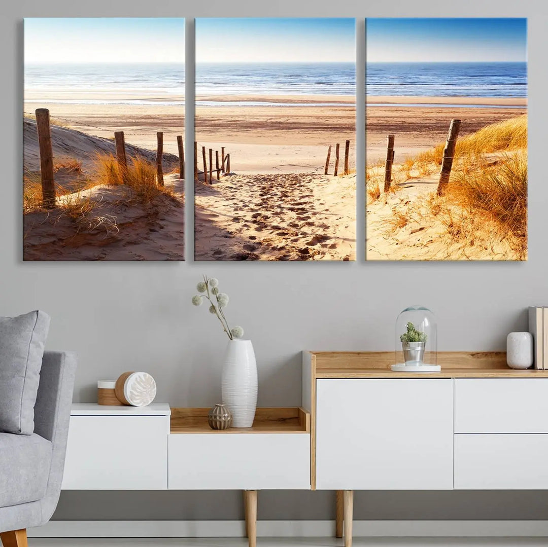 A triptych of Serene Beach Path Canvas Art, a giclee canvas print with gallery wrap, adorns the wall. This stunning coastal sand dunes wall art, crafted with Canon print quality, adds a tranquil touch to the space.