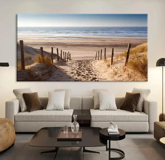 The "Serene Beach Path Canvas – Coastal Landscape Wall Art Triptych – Tranquil Ocean View for Living Room" is tastefully displayed, adding a beautiful coastal touch to the room's ambiance.