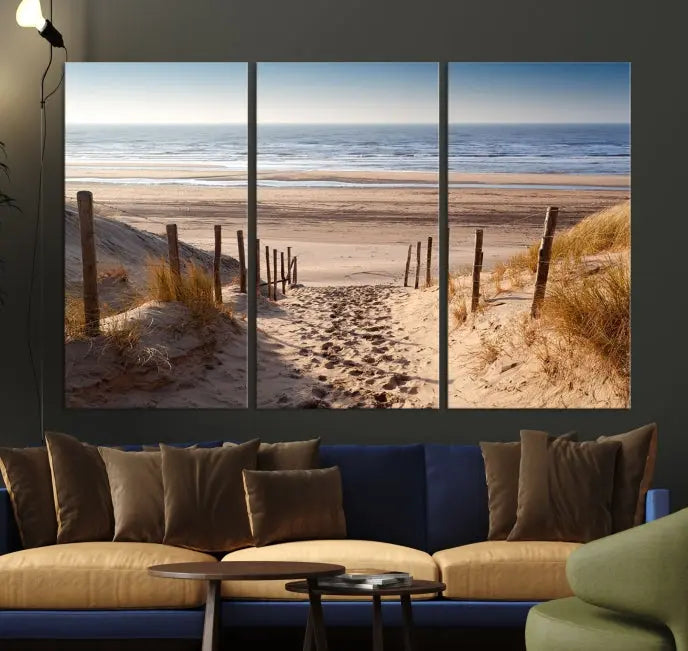 The "Serene Beach Path Canvas – Coastal Landscape Wall Art Triptych – Tranquil Ocean View for Living Room" is tastefully displayed, adding a beautiful coastal touch to the room's ambiance.