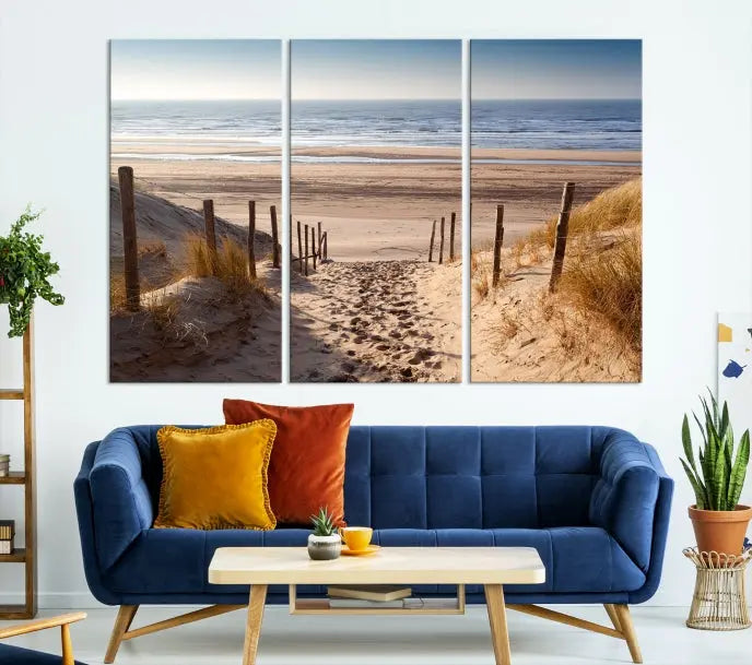 The "Serene Beach Path Canvas – Coastal Landscape Wall Art Triptych – Tranquil Ocean View for Living Room" is tastefully displayed, adding a beautiful coastal touch to the room's ambiance.