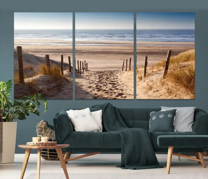 The "Serene Beach Path Canvas – Coastal Landscape Wall Art Triptych – Tranquil Ocean View for Living Room" is tastefully displayed, adding a beautiful coastal touch to the room's ambiance.