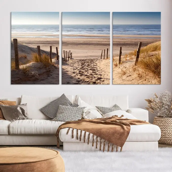 The "Serene Beach Path Canvas – Coastal Landscape Wall Art Triptych – Tranquil Ocean View for Living Room" is tastefully displayed, adding a beautiful coastal touch to the room's ambiance.