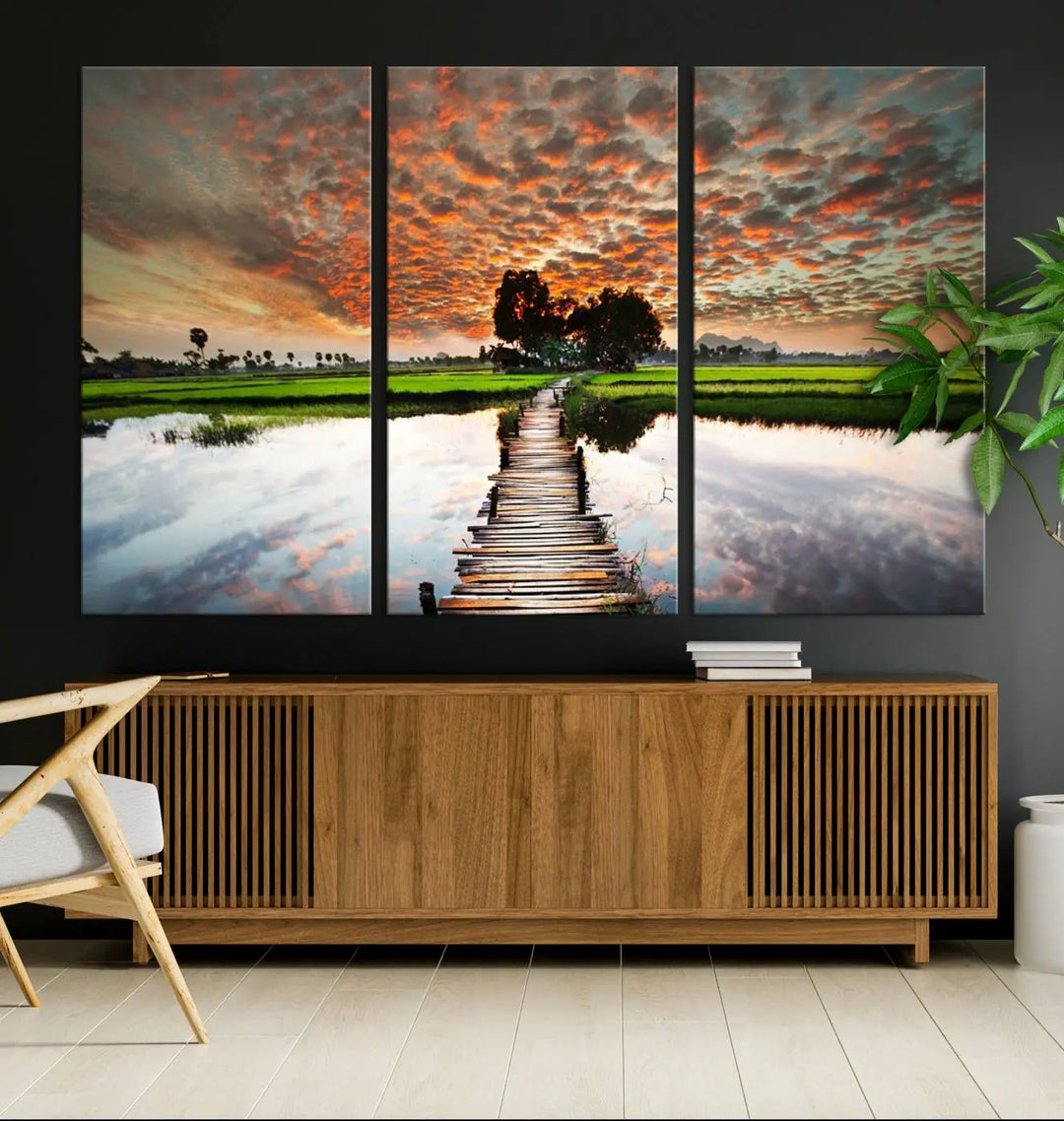 The "Serene Sunset Wooden Bridge Triptych Canvas Art" beautifully depicts a scenic landscape with reflections over water and a vibrant, cloudy sunset sky, making it an ideal choice for textured walls in tranquil spaces.