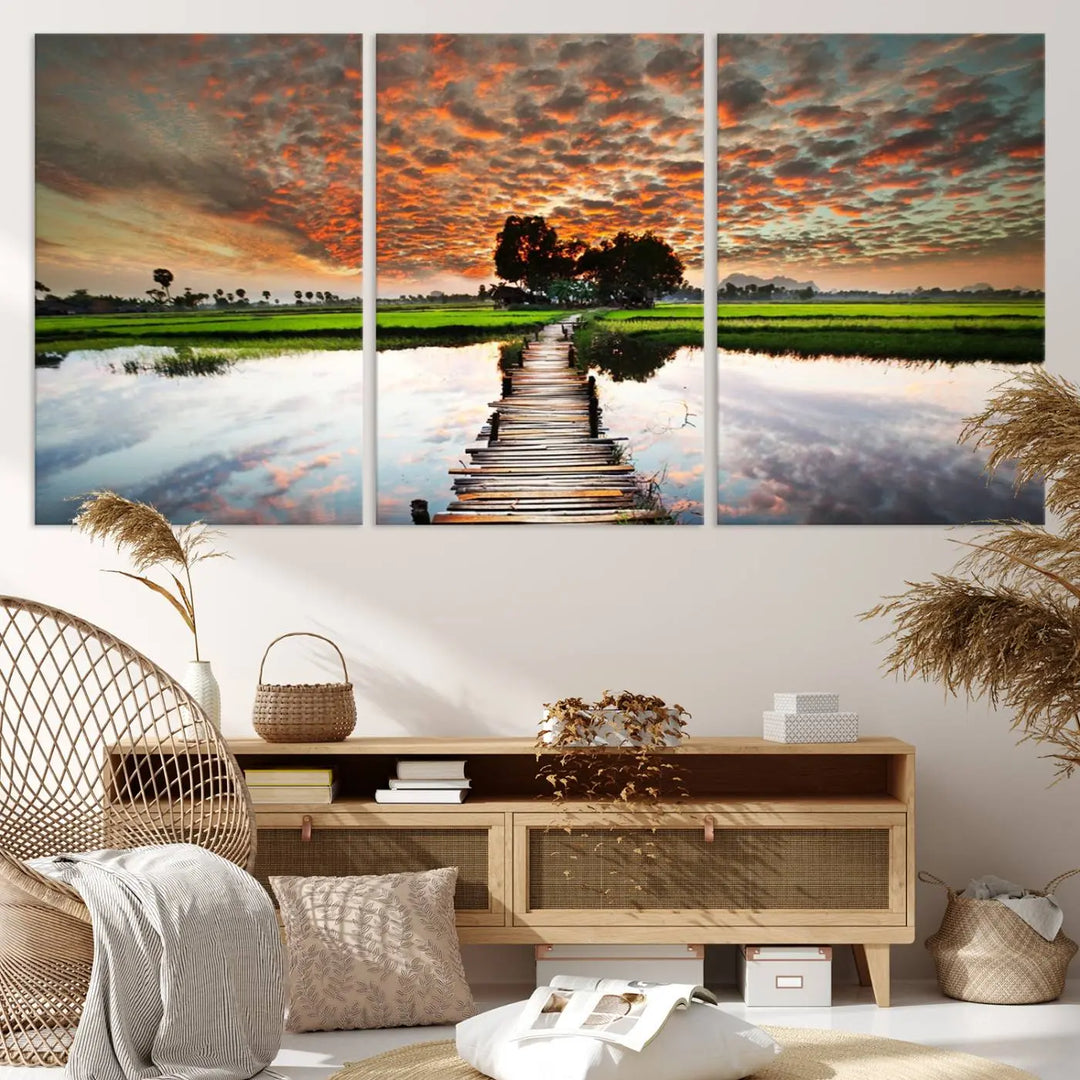 The "Serene Sunset Wooden Bridge Triptych Canvas Art" beautifully depicts a scenic landscape with reflections over water and a vibrant, cloudy sunset sky, making it an ideal choice for textured walls in tranquil spaces.