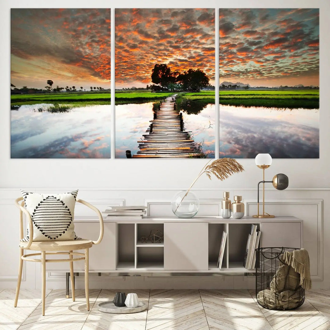 The "Serene Sunset Wooden Bridge Triptych Canvas Art" beautifully depicts a scenic landscape with reflections over water and a vibrant, cloudy sunset sky, making it an ideal choice for textured walls in tranquil spaces.