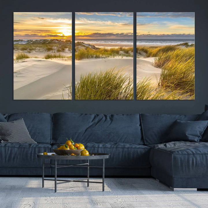 The "Sunrise on The Beach Wall Art Canvas Print" is a set of three museum-quality panels showcasing a beach sunrise with grassy dunes. Each piece includes a UV-protective coating and comes ready to hang for easy installation.