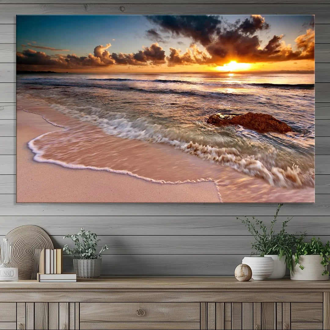 The Sunset Beach Waves Triptych Wall Art, featuring a tropical ocean scene on giclee canvas with a gallery wrap, adorns the wall in a cozy, coastal-themed living room.