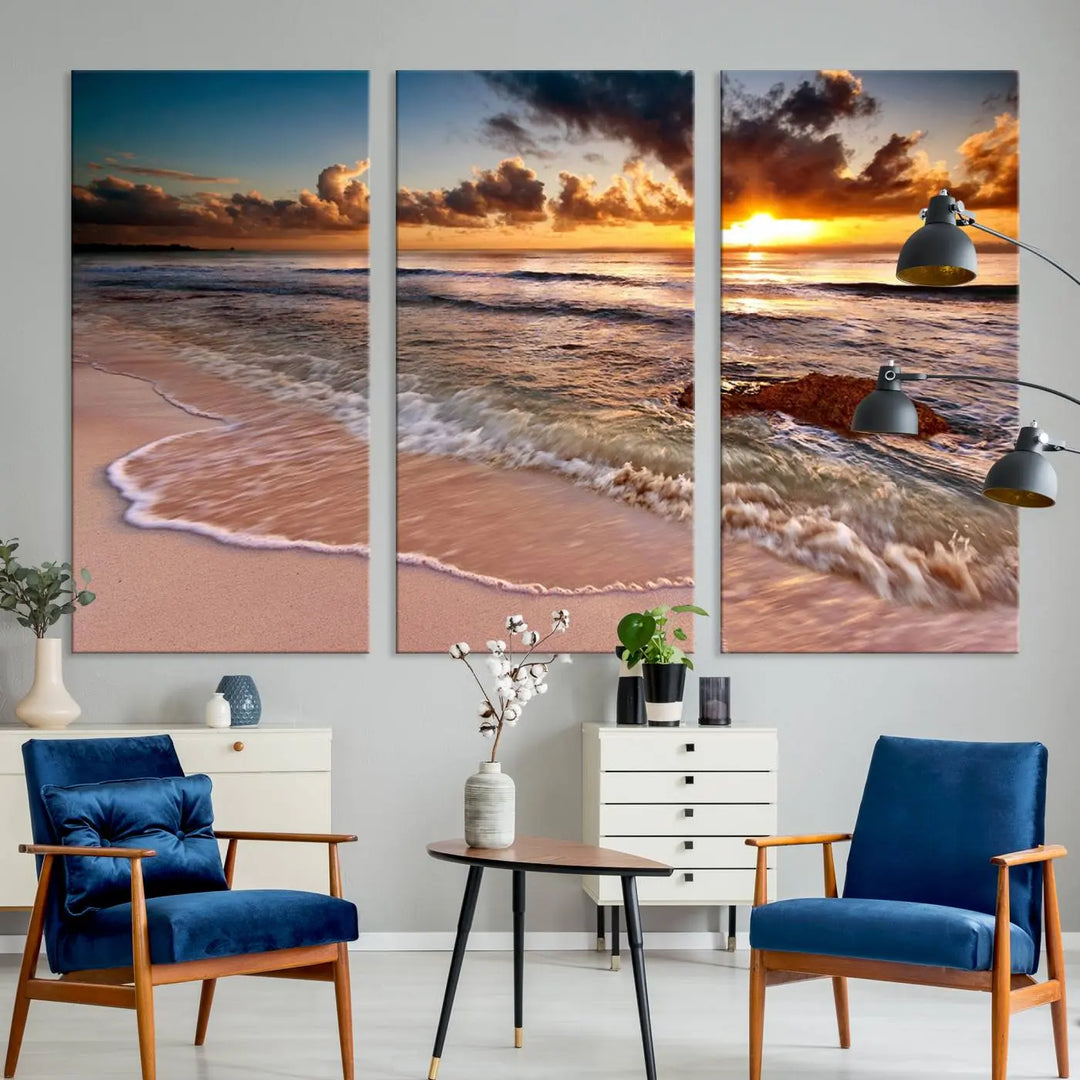 The Sunset Beach Waves Triptych Wall Art, featuring a tropical ocean scene on giclee canvas with a gallery wrap, adorns the wall in a cozy, coastal-themed living room.