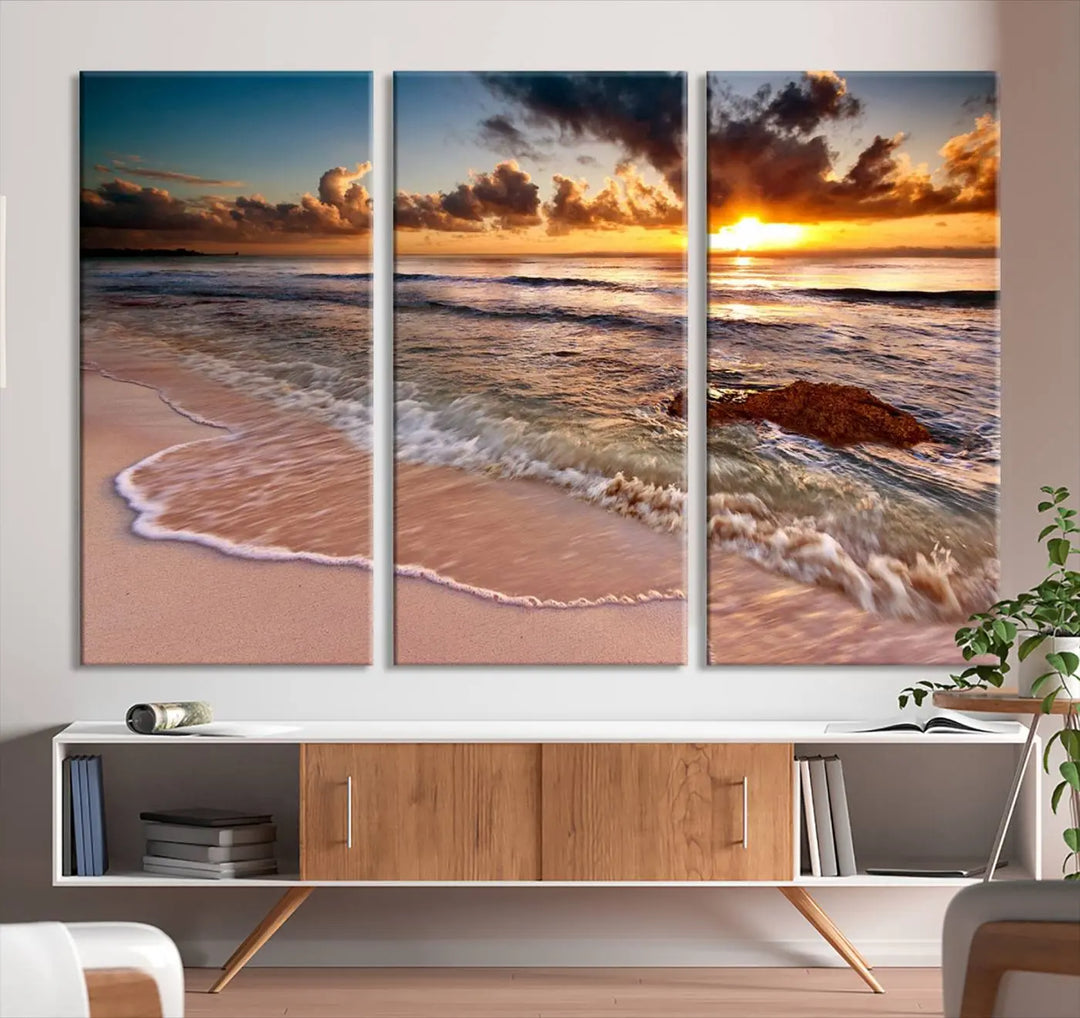 The Sunset Beach Waves Triptych Wall Art, featuring a tropical ocean scene on giclee canvas with a gallery wrap, adorns the wall in a cozy, coastal-themed living room.