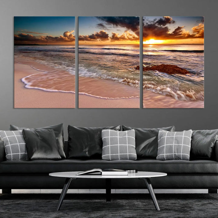 The Sunset Beach Waves Triptych Wall Art, featuring a tropical ocean scene on giclee canvas with a gallery wrap, adorns the wall in a cozy, coastal-themed living room.