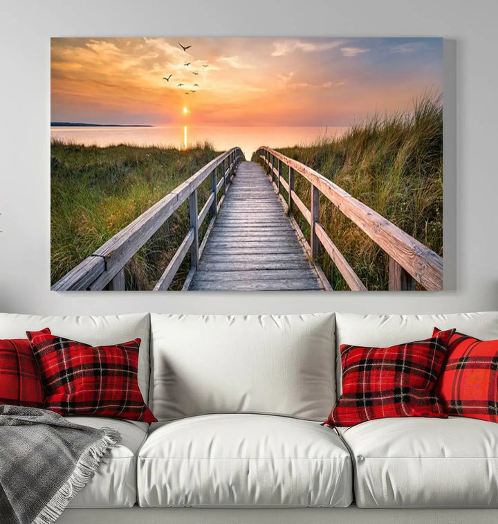 The Sunset Lakeside Pier Wall Art Canvas Print depicts a boardwalk leading towards a sunset over the ocean, framed by grassy dunes. Each piece is meticulously hand-assembled using museum-quality canvas to guarantee durability and vibrant colors.