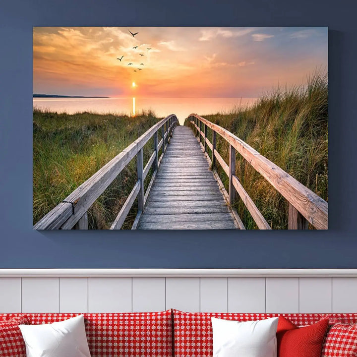 The Sunset Lakeside Pier Wall Art Canvas Print depicts a boardwalk leading towards a sunset over the ocean, framed by grassy dunes. Each piece is meticulously hand-assembled using museum-quality canvas to guarantee durability and vibrant colors.