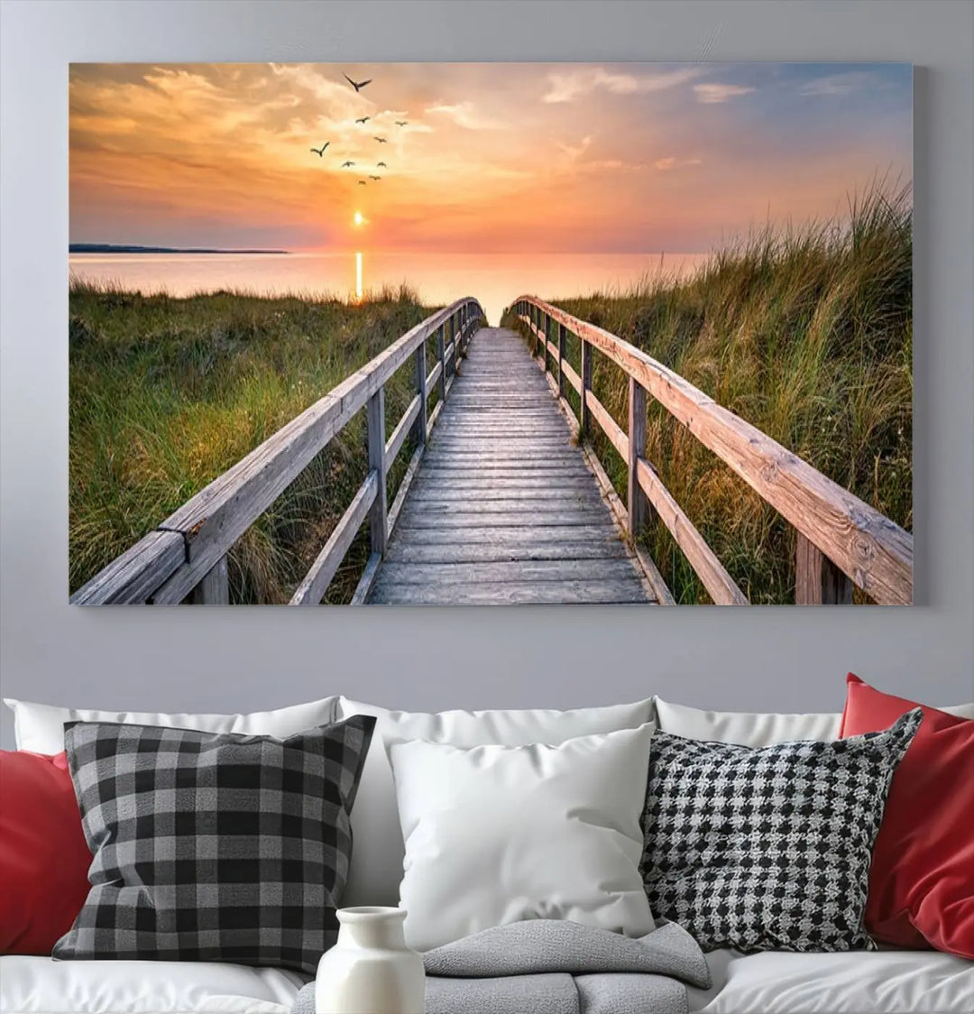 The Sunset Lakeside Pier Wall Art Canvas Print depicts a boardwalk leading towards a sunset over the ocean, framed by grassy dunes. Each piece is meticulously hand-assembled using museum-quality canvas to guarantee durability and vibrant colors.