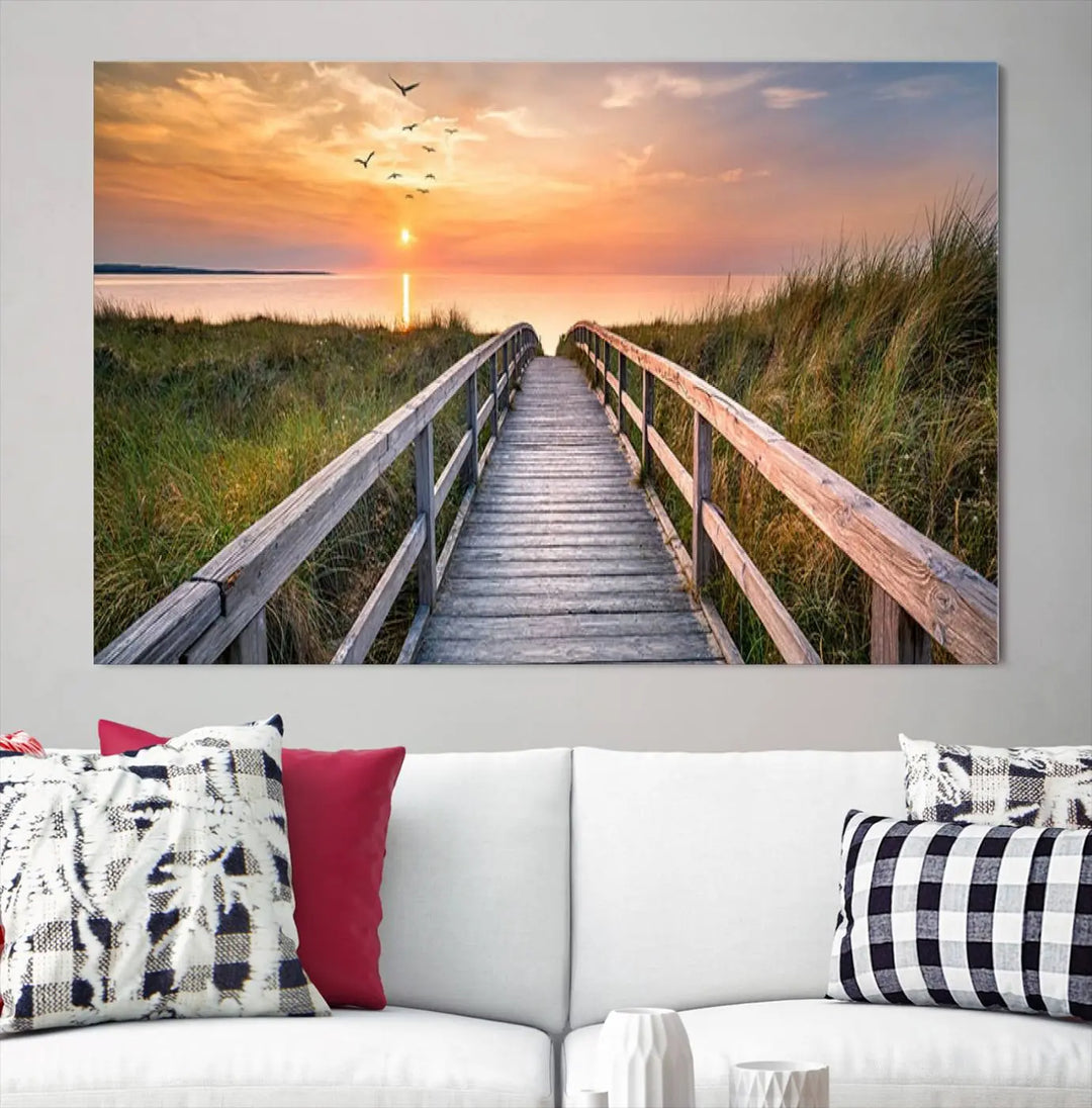 The Sunset Lakeside Pier Wall Art Canvas Print depicts a boardwalk leading towards a sunset over the ocean, framed by grassy dunes. Each piece is meticulously hand-assembled using museum-quality canvas to guarantee durability and vibrant colors.