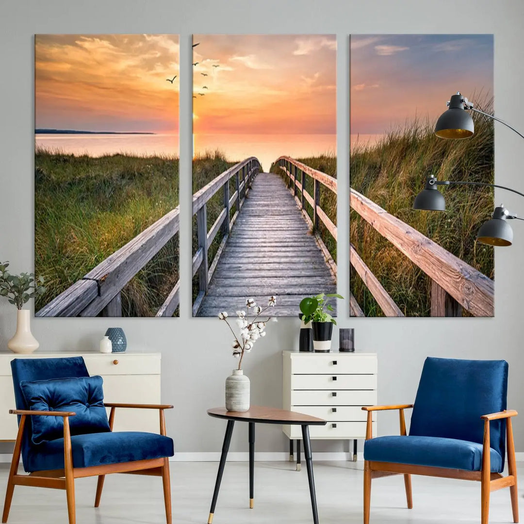 The Sunset Lakeside Pier Wall Art Canvas Print depicts a boardwalk leading towards a sunset over the ocean, framed by grassy dunes. Each piece is meticulously hand-assembled using museum-quality canvas to guarantee durability and vibrant colors.