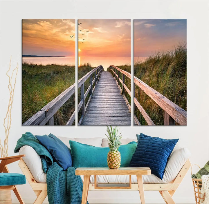 The Sunset Lakeside Pier Wall Art Canvas Print depicts a boardwalk leading towards a sunset over the ocean, framed by grassy dunes. Each piece is meticulously hand-assembled using museum-quality canvas to guarantee durability and vibrant colors.