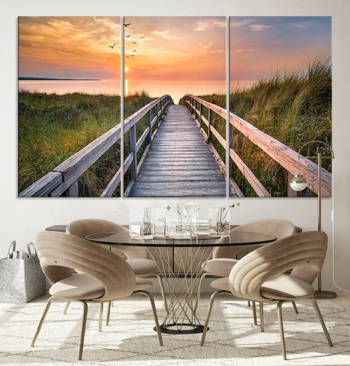 The Sunset Lakeside Pier Wall Art Canvas Print depicts a boardwalk leading towards a sunset over the ocean, framed by grassy dunes. Each piece is meticulously hand-assembled using museum-quality canvas to guarantee durability and vibrant colors.