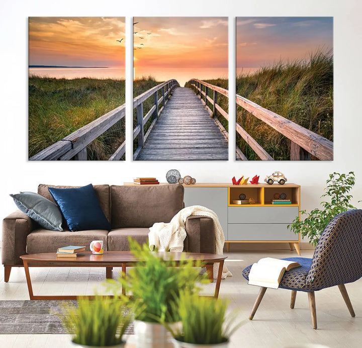 The Sunset Lakeside Pier Wall Art Canvas Print depicts a boardwalk leading towards a sunset over the ocean, framed by grassy dunes. Each piece is meticulously hand-assembled using museum-quality canvas to guarantee durability and vibrant colors.