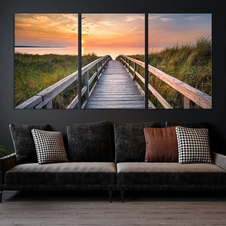 The Sunset Lakeside Pier Wall Art Canvas Print depicts a boardwalk leading towards a sunset over the ocean, framed by grassy dunes. Each piece is meticulously hand-assembled using museum-quality canvas to guarantee durability and vibrant colors.