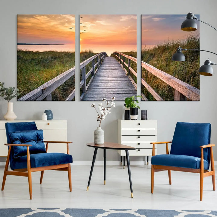 The Sunset Lakeside Pier Wall Art Canvas Print depicts a boardwalk leading towards a sunset over the ocean, framed by grassy dunes. Each piece is meticulously hand-assembled using museum-quality canvas to guarantee durability and vibrant colors.