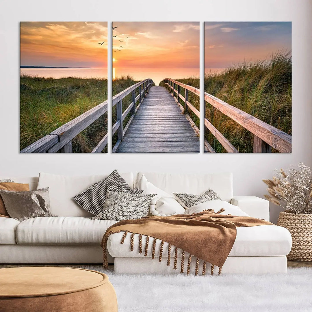 The Sunset Lakeside Pier Wall Art Canvas Print depicts a boardwalk leading towards a sunset over the ocean, framed by grassy dunes. Each piece is meticulously hand-assembled using museum-quality canvas to guarantee durability and vibrant colors.