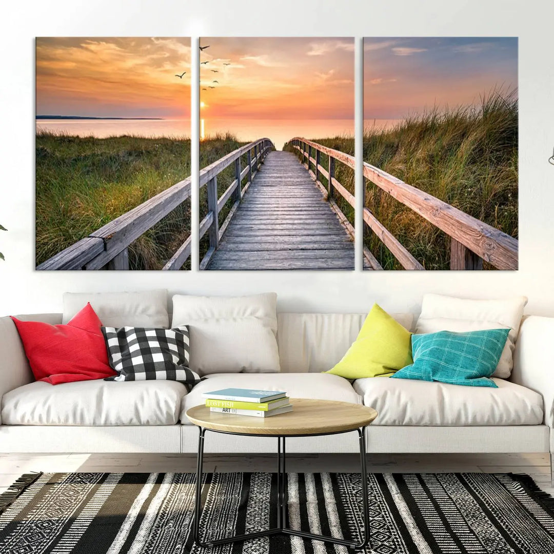 The Sunset Lakeside Pier Wall Art Canvas Print depicts a boardwalk leading towards a sunset over the ocean, framed by grassy dunes. Each piece is meticulously hand-assembled using museum-quality canvas to guarantee durability and vibrant colors.