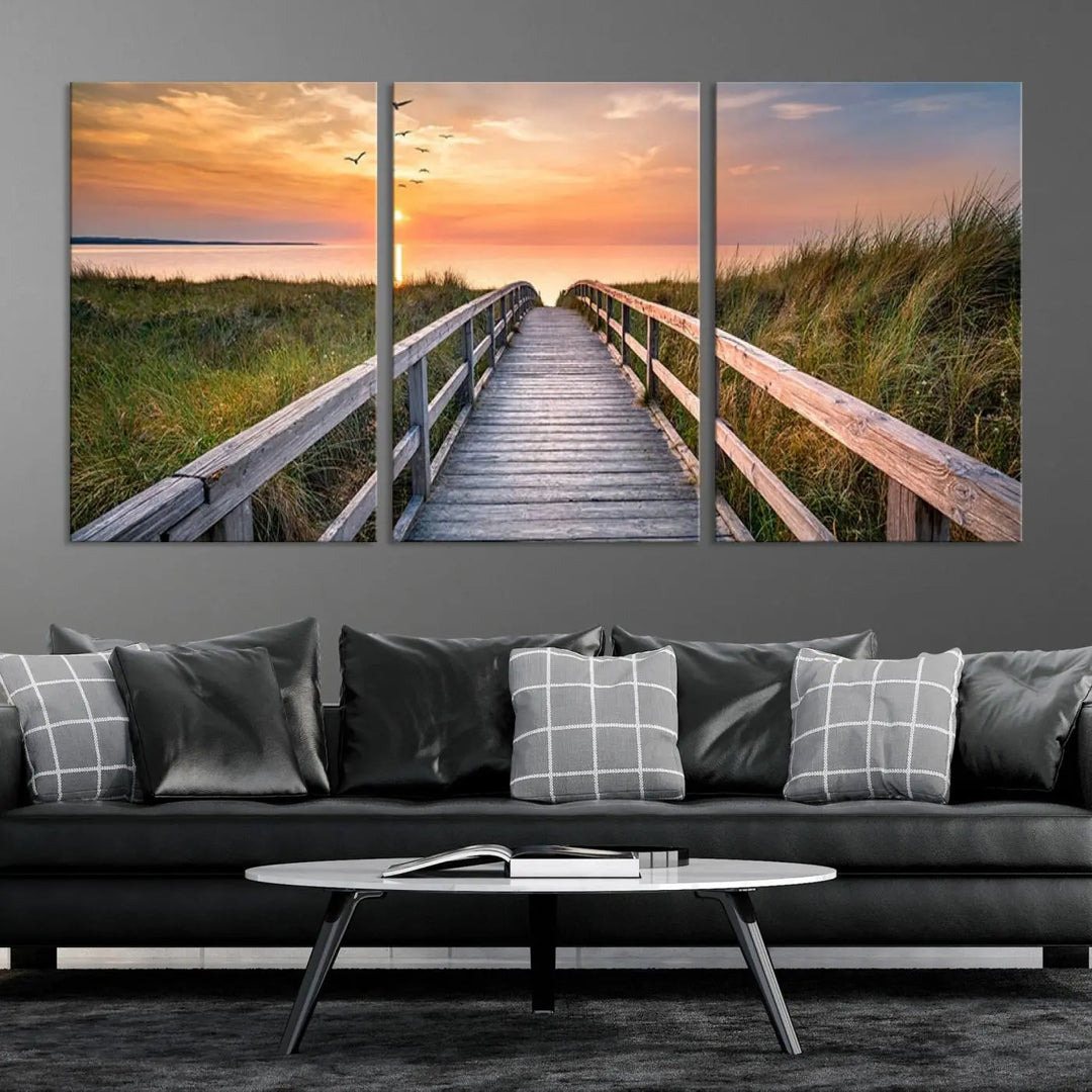 The Sunset Lakeside Pier Wall Art Canvas Print depicts a boardwalk leading towards a sunset over the ocean, framed by grassy dunes. Each piece is meticulously hand-assembled using museum-quality canvas to guarantee durability and vibrant colors.