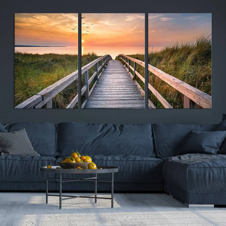 The Sunset Lakeside Pier Wall Art Canvas Print depicts a boardwalk leading towards a sunset over the ocean, framed by grassy dunes. Each piece is meticulously hand-assembled using museum-quality canvas to guarantee durability and vibrant colors.