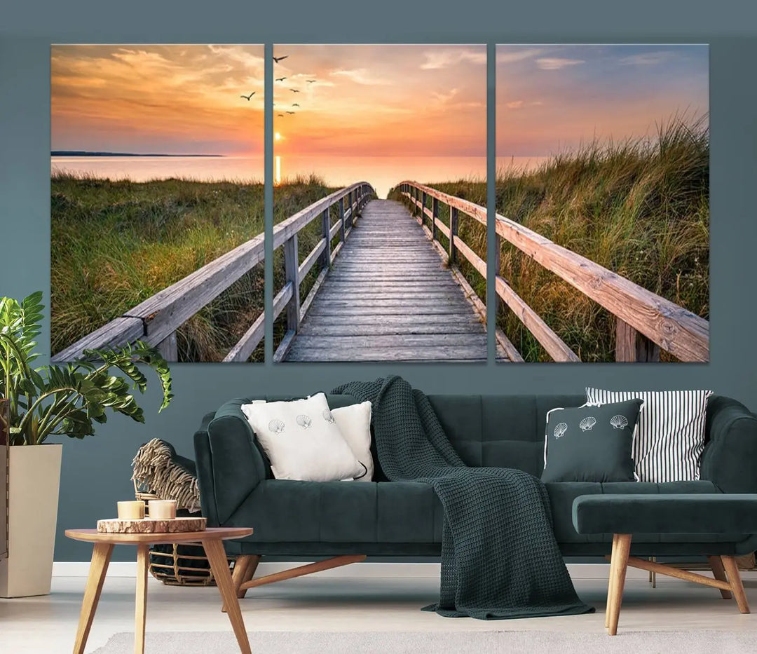 The Sunset Lakeside Pier Wall Art Canvas Print depicts a boardwalk leading towards a sunset over the ocean, framed by grassy dunes. Each piece is meticulously hand-assembled using museum-quality canvas to guarantee durability and vibrant colors.