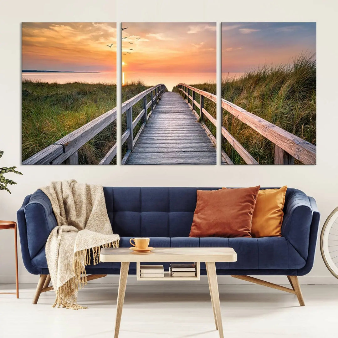 The Sunset Lakeside Pier Wall Art Canvas Print depicts a boardwalk leading towards a sunset over the ocean, framed by grassy dunes. Each piece is meticulously hand-assembled using museum-quality canvas to guarantee durability and vibrant colors.