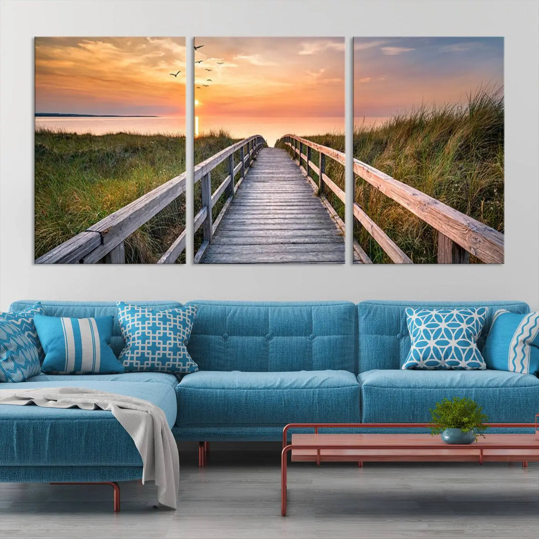 The Sunset Lakeside Pier Wall Art Canvas Print depicts a boardwalk leading towards a sunset over the ocean, framed by grassy dunes. Each piece is meticulously hand-assembled using museum-quality canvas to guarantee durability and vibrant colors.