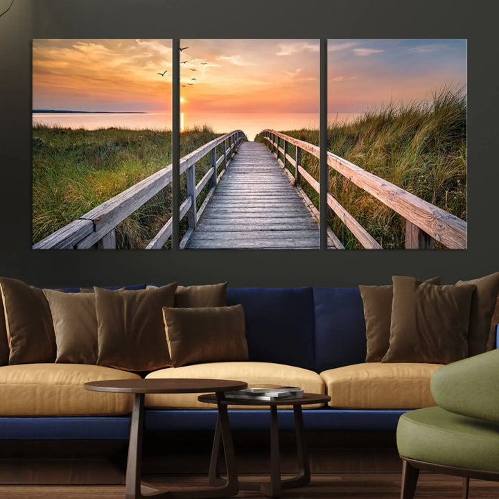 The Sunset Lakeside Pier Wall Art Canvas Print depicts a boardwalk leading towards a sunset over the ocean, framed by grassy dunes. Each piece is meticulously hand-assembled using museum-quality canvas to guarantee durability and vibrant colors.