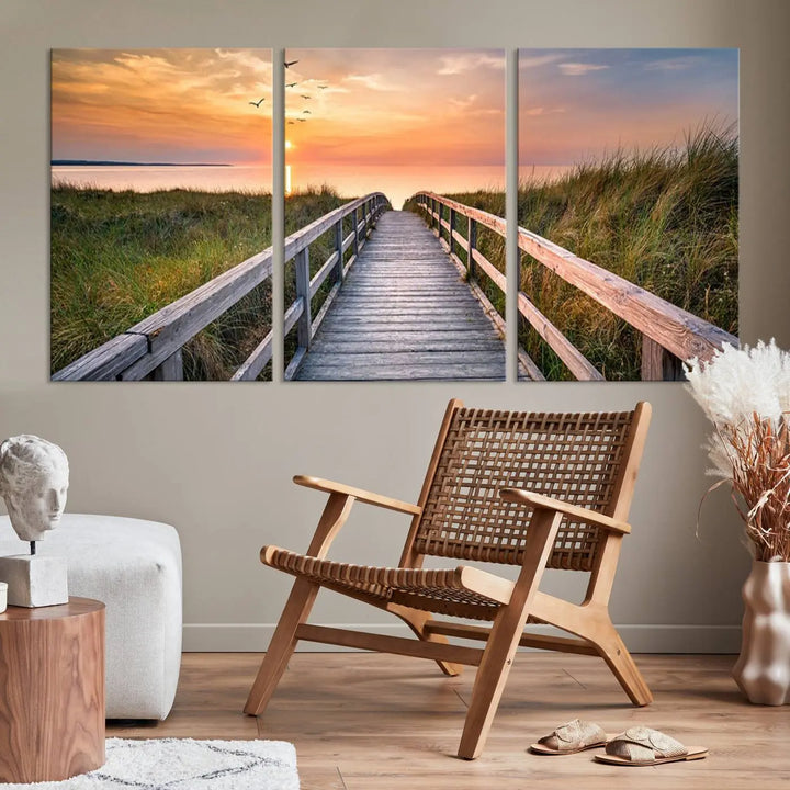 The Sunset Lakeside Pier Wall Art Canvas Print depicts a boardwalk leading towards a sunset over the ocean, framed by grassy dunes. Each piece is meticulously hand-assembled using museum-quality canvas to guarantee durability and vibrant colors.